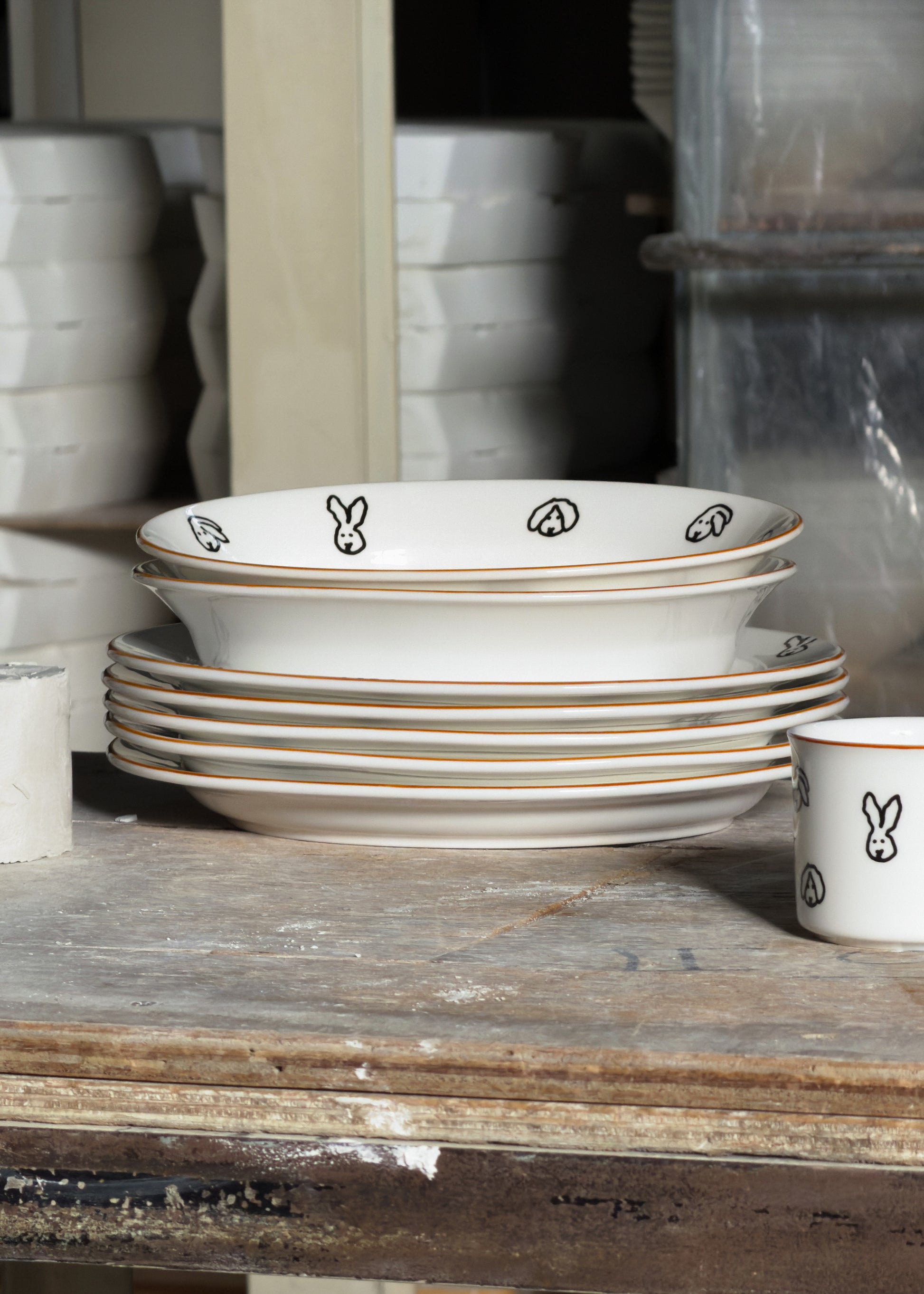 Stack of white bowls with black and brown designs on a wooden surface.