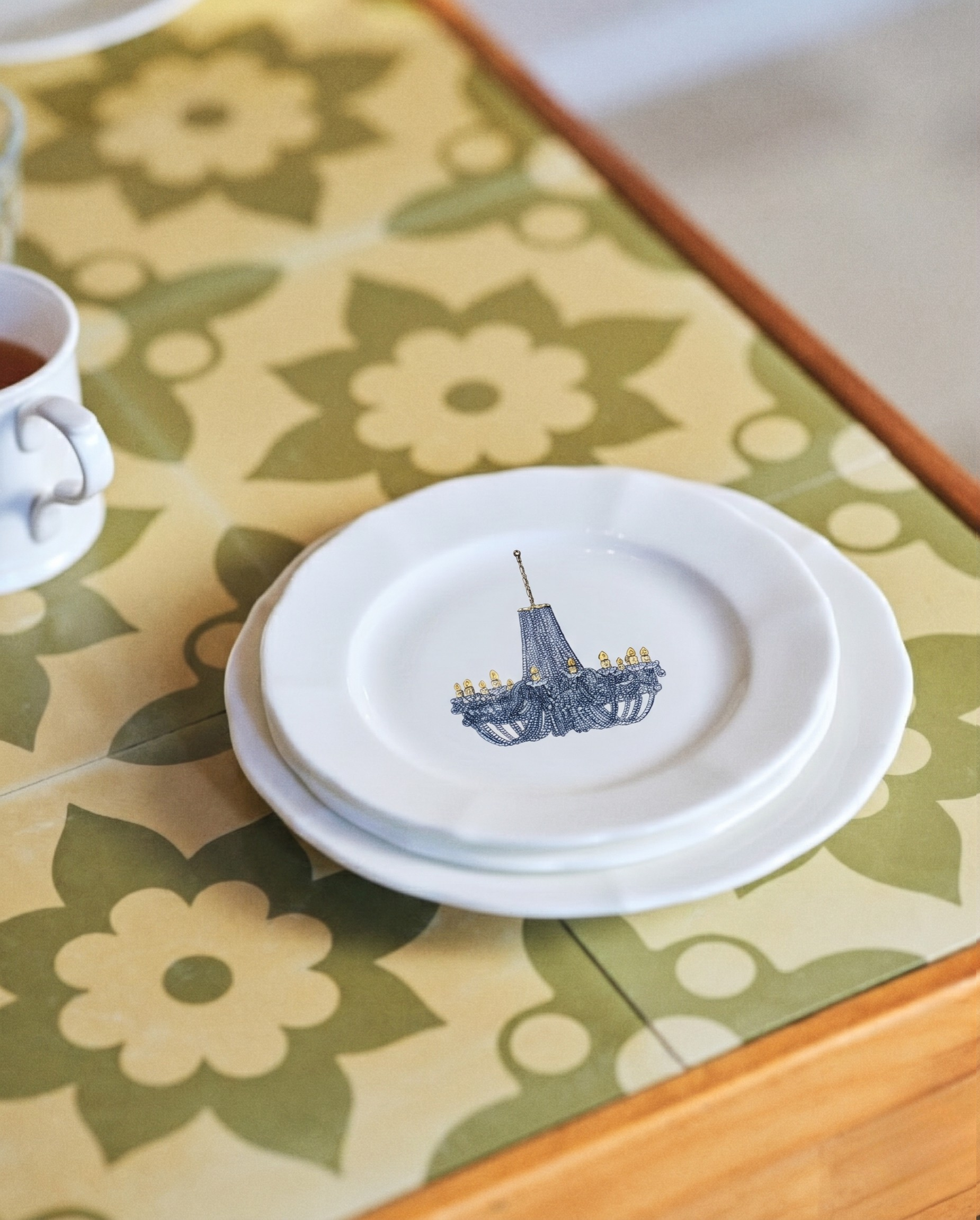 White plate with a blue design on a floral tablecloth