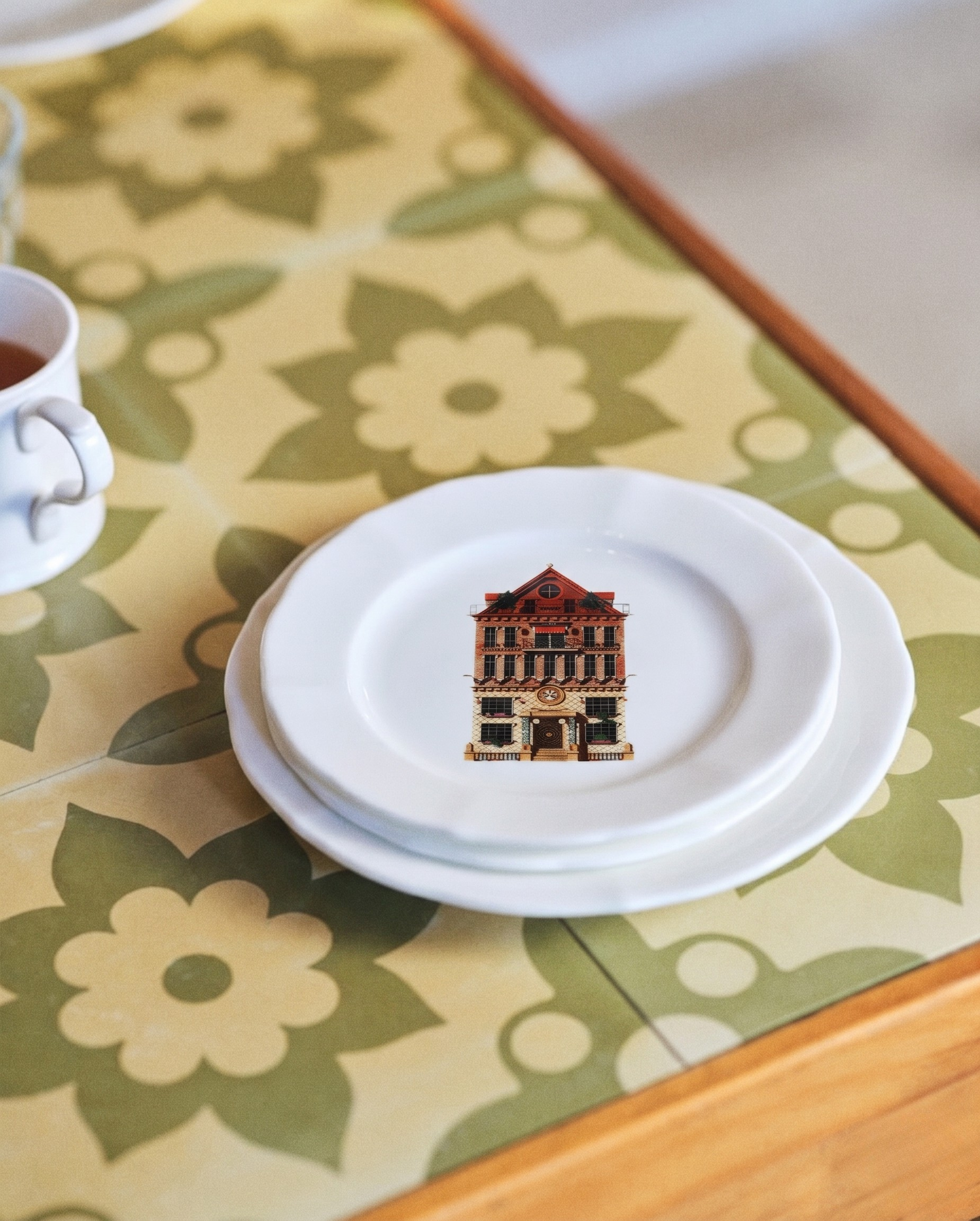 White plate with a building design on a floral tablecloth