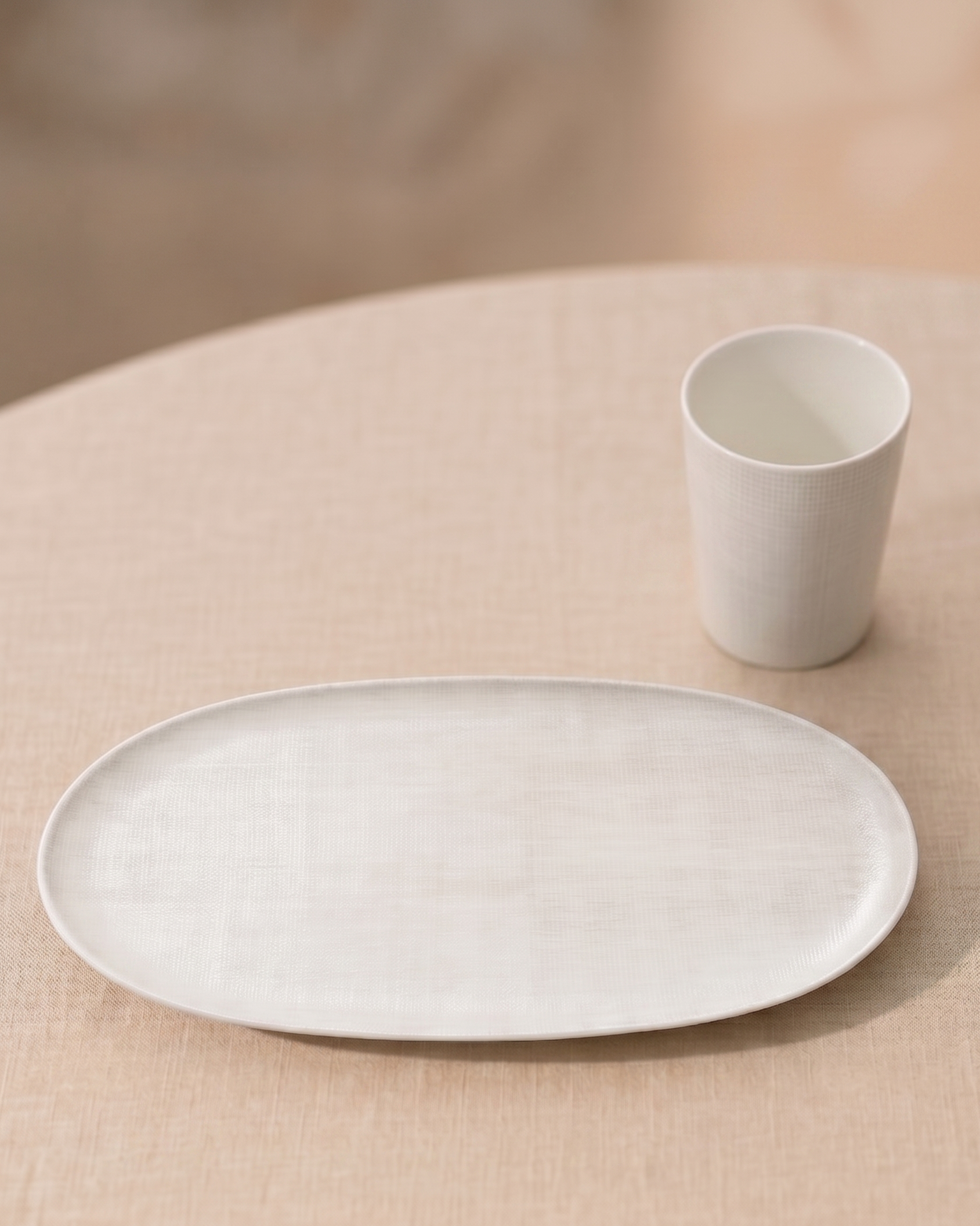 White ceramic plate and cup on a beige surface