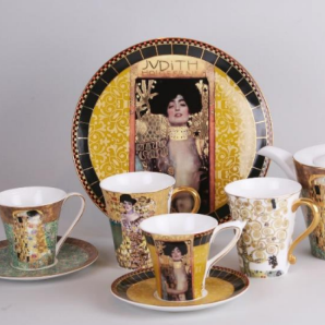 Decorative teacups and saucers with artistic designs on a gray background