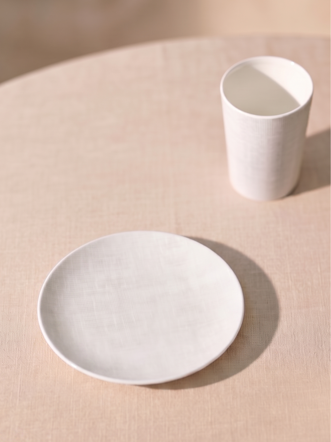White ceramic plate and cup on a beige surface